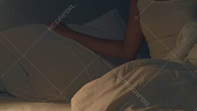 Beautiful Asian young woman sleeping cozily in her bedroom. Indian female hand turning off on light switch near bed in room at