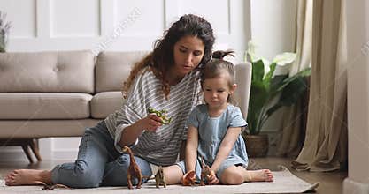 Happy bonding family of two playing with dinosaurs toys.