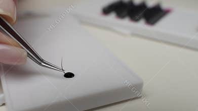 Eyelash Extension Procedure. Close-up of a master at work artificial eyelash extensions material. Hands of the master