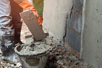 worker plastering cement on wall for building house