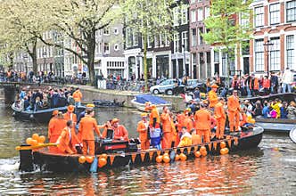 Amsterdam, Netherlands - April 27, 2019: People on party boats dressed in national orange color while celebrating the Kings day,