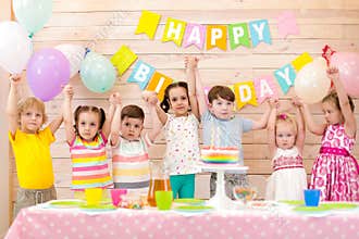Large group of children happily hold their hands up