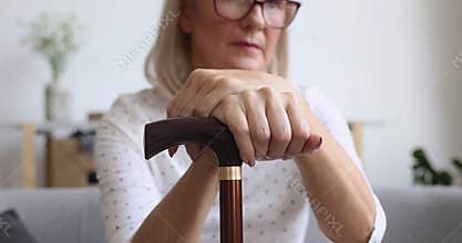 Old woman holding cane stick in hands, close up view