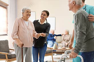 Care workers helping to elderly patients to walk in hospice