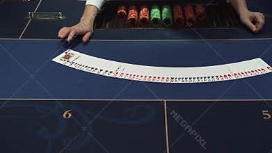 Dealer beautifully lays out cards on the card table in the casino