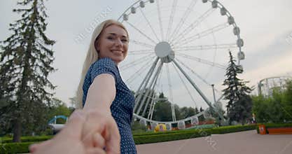 Pov shot of man holding hand with young girlfriend in amusement park. Follow me concept
