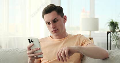 Puzzled man with mobile phone on sofa