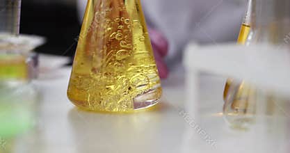 Liquid is added flask with yellow oily liquid carrying out chemical experiment