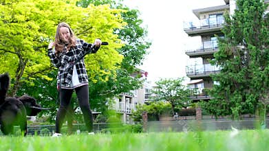 Bernedodle completely black dog walking with a girl in a plaid shirt jumping on her trying to pick up leash face