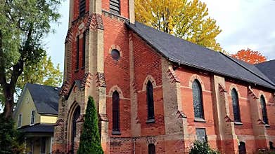 Slow camera movement of the exterior of a church and the autumn leaf colour of a small town