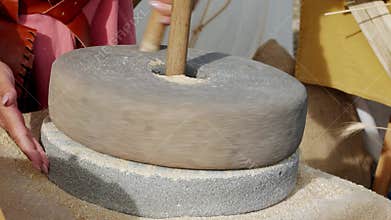 hand using a large authentic millstone, medieval utensil for grinding grains