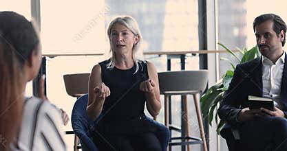 Serious confident engaged mature business woman speaking to multiethnic team