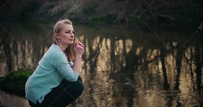 Woman looking around while crouching by lake
