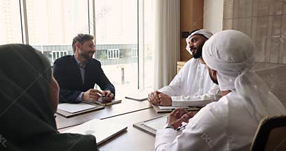 Multicultural business partners shake hands at meeting in boardroom