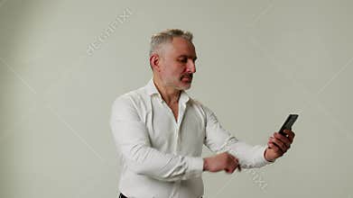 A middle aged man uses a smartphone, moves it away due to eye fatigue, poor vision or farsightedness. A businessman or