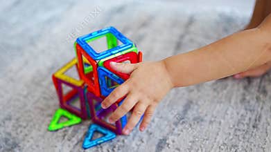 Little girl playing colorful magnet plastic blocks kit at home. The child playing educational games. Early childhood
