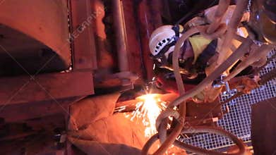Footage of rope access industrial technician fitters, boilermaker wearing fully safety harness, helmet welding mask eyes protectio