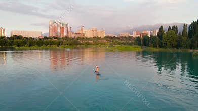 Man ride on SUP board in the mountain lake