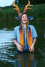 Portrait of the teenage Girl staying waist-deep in the lake and happilly laughing