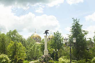 Eagle stone statue and Christian church with golden domes and cross in the Park