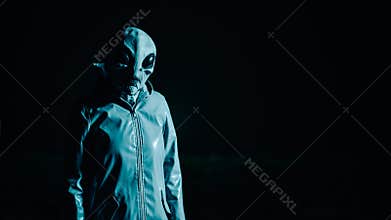 Portrait of spooky alien in dark black background. Scary mask, vinyl smooth raincoat. UFO, extraterrestrial life
