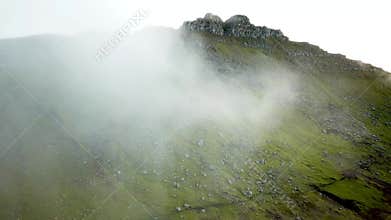 Aerial view of amazing mist Faroese nature, foggy green hills and rocky cliffs.