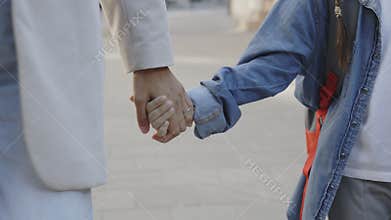 Close up shot of childs hand reaching for mothers loving hand. Parent and daughter holding hands on urban background.