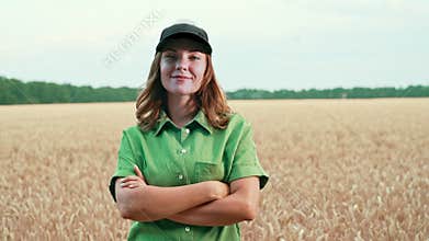 Portrait of young woman agronomist in wheat field. Female farmer with smile looks at rich summer harvest. Agricultural