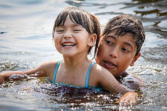 Boy and a girl are having fun swimming in a lake in summer