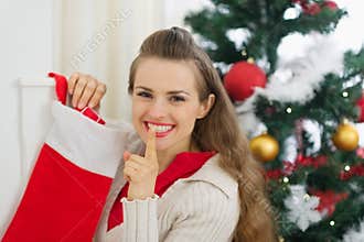 Smiling young woman put gift in Christmas socks