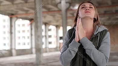 A young woman prays to God with folded hands. The concept of faith in the religion of Christianity