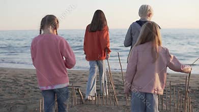 Children walk on the sandy beach and play with sticks