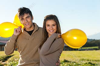 Cute teen couple outdoors with balloons.