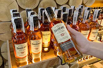 Hand holding Oakheart spiced rum Bacardi 500 ml rum bottle in a supermarket shelf closeup.