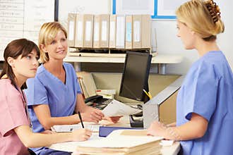 Three Nurses Working At Nurses Station
