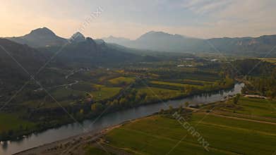 aerial scenic landscape with green fields, meadows, curved mountain river and mountain ridge with high mountains and
