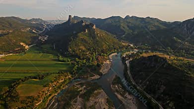 aerial scenic landscape with green fields, meadows, curved mountain river and mountain ridge with high mountains and