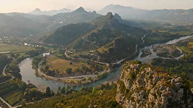 aerial scenic landscape with green fields, meadows, curved mountain river and mountain ridge with high mountains and