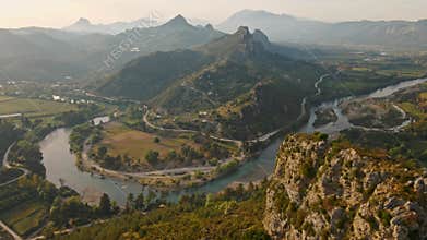 aerial scenic landscape with green fields, meadows, curved mountain river and mountain ridge with high mountains and