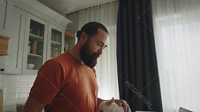 Handsome business man drink juice at home. His funny pet dog looking at owner and asks for play. Online working from