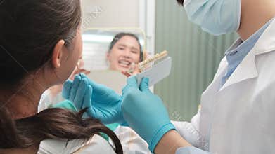 Asian male dentist explains teeth care to a female patient in a dental clinic.