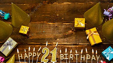 Happy birthday 21. Top view of the golden letters of the candle with the number happy birthday, the background of the gift boxes