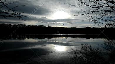 Video silhouette of wind farm with turning wind turbines reflected in lake