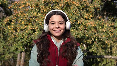 childhood of glad teen girl listen music in wireless headphones. teen girl listen music