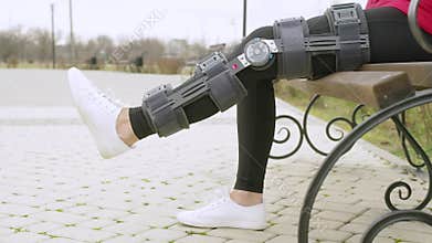 Woman wearing knee brace or orthosis after leg surgery working out in the park