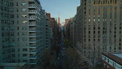 Fly over historic marble memorial Washington Square Arch. Revealing long straight street lined by tall buildings. New