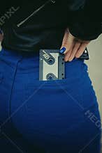 Stylized photo with a grain of woman holding audio cassette in a pocket