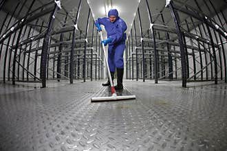 Worker uniform cleaning floor in storehouse