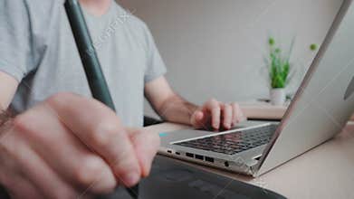 Man takes stylus from drawing tablet and begins to draw. Hand close-up. Concept of retouching and digital illustrations