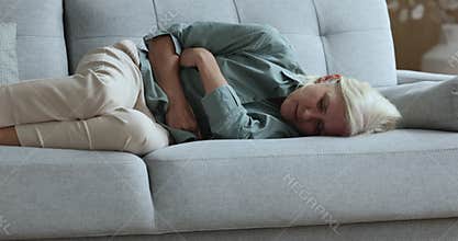 Sick aged woman lying, touch belly, suffers from abdomen ache